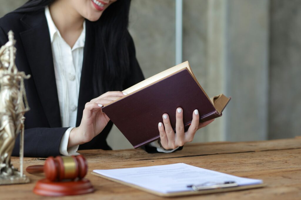 Charming young woman lawyer is reading a law book and working at a desk in a law firm.